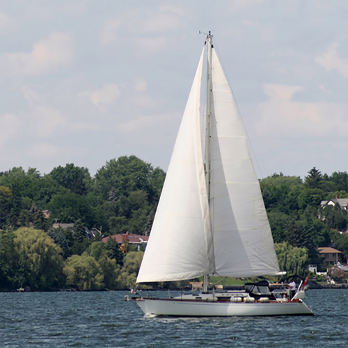 White sailboat on lake with green tree-lined shore — scent inspiration for Bay Breeze fragrance oil