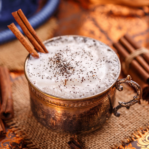Frothy spiced drink with cinnamon stick in copper cup — scent inspiration for Vanilla Chai fragrance oil