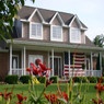 Two-story house with a front porch and American flag — scent inspiration for Home Sweet Home fragrance oil