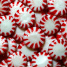 Pile of red-and-white striped round peppermint candies — scent inspiration for Peppermint fragrance oil