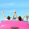 Couple raising arms in a pink convertible, blue sky — scent inspiration for Endless Weekend fragrance oil