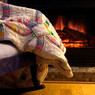 Patchwork quilt draped on a chair before a fireplace — scent inspiration for Fireside fragrance oil