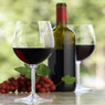 Two glasses of red wine with a bottle and grapes — scent inspiration for Merlot fragrance oil