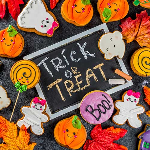 Halloween-themed display with orange pumpkins, black candles, and spooky decorations on a rustic wooden table.