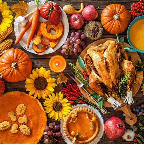 Warm Thanksgiving setting with a pumpkin pie, decorative pumpkins, fall leaves, and a lit candle on a cozy wooden table—evoking the scents and comfort of the holiday season.