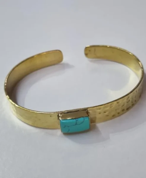 Brass Bangle Hammered Amazonite

This brass and gemstone cuff bangle features a wide, flat band with a hammered texture that provides a rustic, handcrafted finish and the open-back design allows for an adjustable fit.  

Brass is an alloy; it is a beautiful blend of copper and zinc, and it is nickel-free.
It possesses a natural, earthy yellow hue that looks remarkably like solid gold without the price!

All our brass jewelry is handmade in Rajasthan in North India