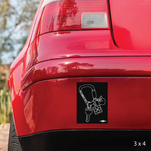 Black magnet on a car bumper with line drawing of a carabiner holding a key, the New Disabled South logo, and a peach charm. Black magnet on a car bumper with line drawing of a carabiner holding a key, the New Disabled South logo, and a peach charm.