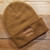 A tan beanie embroidered with the Headlong Farm brand and a generous cuff