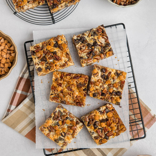 SusieCakes 7 Layer Bars topped with chocolate chips, butterscotch chips, coconut, and pecans on a graham cracker crust