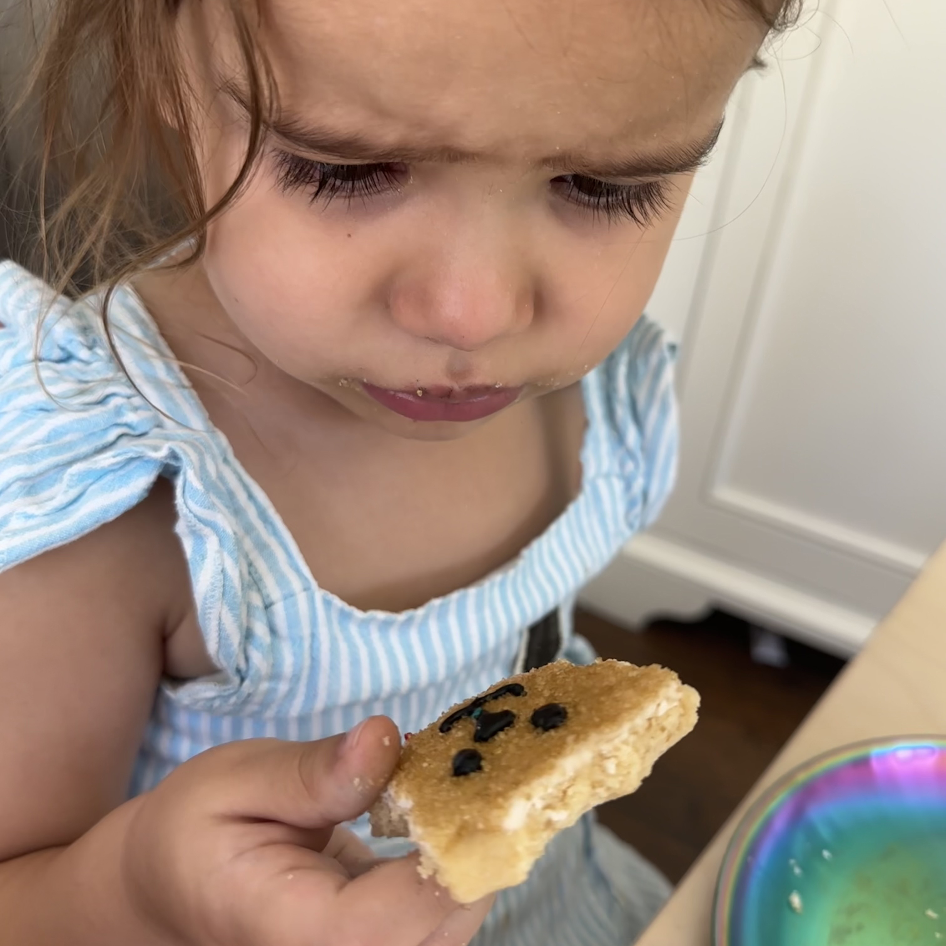 Little Girl looking at dog cookie