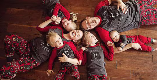a family laying in a circle on the floor wearing 'don't wake the bear' matching pajamas