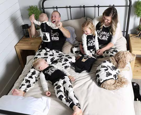 mom, dad, children and dog laying in bed all wearing a bear themed matching pajama