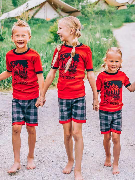 three kids wearing short sleeve pajamas walking outside and holding hands