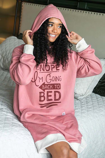 woman sitting on bed wearing a pink sleep hoodie