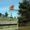 Flying Pig Weathervane on blue sky background.