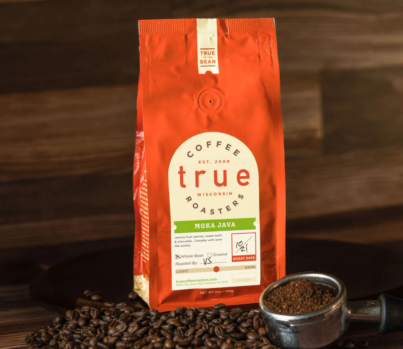 A bag of True Coffee Roasters Moka Java beside roasted beans and a portafilter