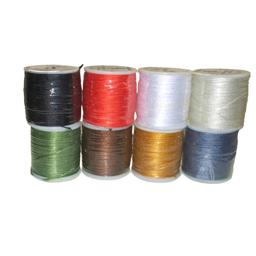 Spools of extra strong sewing thread sitting vertically with a white sticker on top featuring the logo. The thread is covered in a clear wrap protecting the thread. Black, Red, White, Cream, Green, Brown, Mustard, Blue threads in that order.