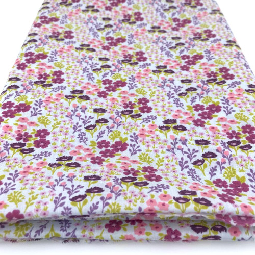 Image shows a sky-blue polycotton fabric printed with small, colourful flowers in various shades. The pattern is evenly scattered, creating a fresh, summery look. The fabric is 112cm wide with a smooth texture and shown folded in a rectangle.