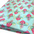 Image shows a medium weight light aqua cotton fabric, 137cm wide, printed with a colourful floral design featuring large flowers and leafy shapes resembling cabbage leaves. The design is uniform with no set direction. Folded in a rectangle shown at an angle.