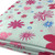 Image shows a mint green polycotton fabric printed with a repeating pattern of varying sizes of  hearts circles and flowers in soft, summery shades of pink and blue. The fabric is 112cm wide with a smooth texture and lightweight feel. Folded in a rectangle photographed at an angle.