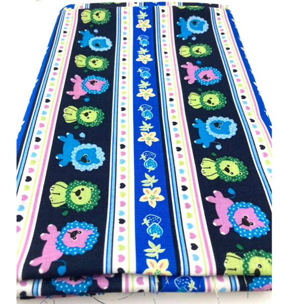 Playful lions in blue, pink and green with polka dot mains on a navy blue stripe. Either side are blocks of whte with pink and green stripes and colourful hearts down the centre.  This printed cotton fabric 137cm wide cotton, nursery print fabric, folded in a rectangle.
