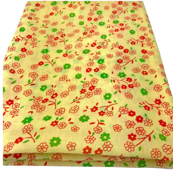 Image shows a yellow polycotton fabric printed with small sprigs of red and green flowers. The pattern is evenly scattered, creating a vintage summer look. The fabric is 112cm wide and has a lightweight, smooth texture shown folded in a rectangle.