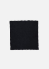 A square swatch of fabric in black with a zigzag edge, featuring a logo in the corner.