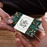 A hand holding a vibrant, full-colour loyalty card featuring a green design with various playful patterns and a logo.