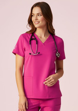 A women's pink V-neck scrub top is displayed, featuring short sleeves and a classic fit, with a stethoscope around the neck.