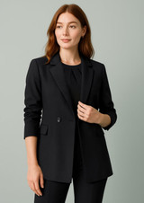 A black longline double-breasted blazer featuring a sleek design and a single button detail, worn by a model.