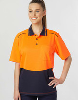 A woman models a bright orange and navy blue unisex polo shirt with a pocket and contrasting details.