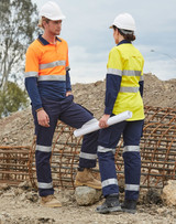 Two workers in high-visibility workwear, wearing orange and yellow shirts with navy pants, on a construction site. Two workers in high-visibility workwear, wearing orange and yellow shirts with navy pants, on a construction site.
