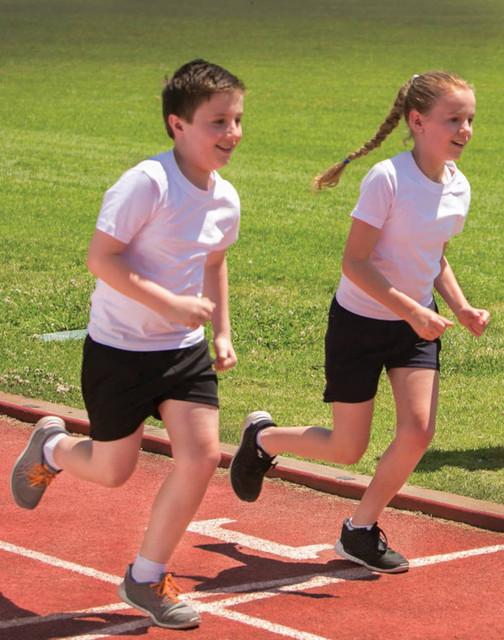 Two children running on a track, wearing white T-shirts and black shorts.