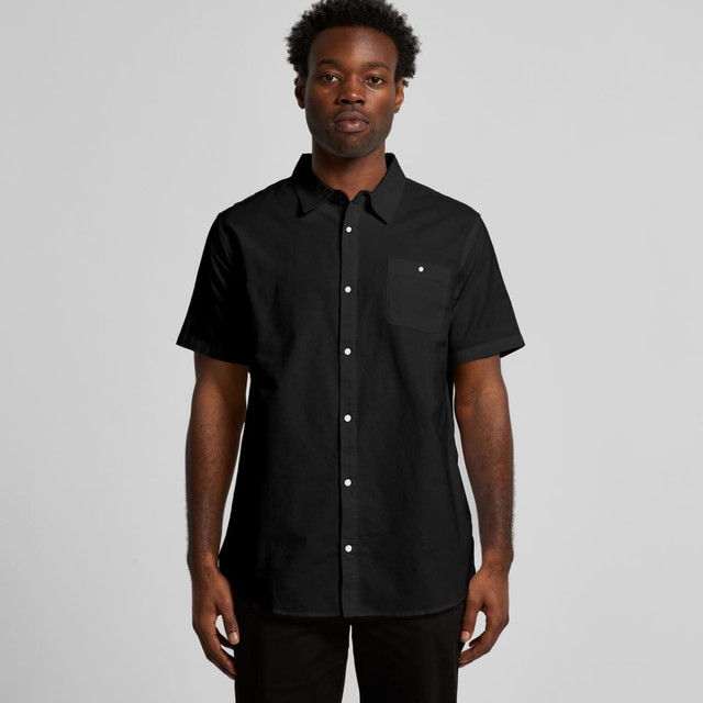 A black short-sleeved button-up shirt with a pocket. The model is wearing it against a plain background.