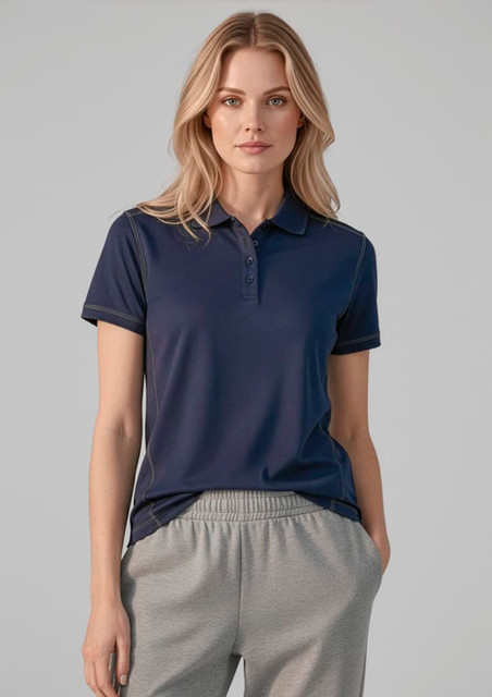 A woman wearing a navy short sleeve polo shirt, paired with light grey sweatpants, with a logo on the shirt.