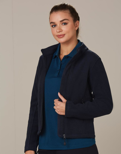 A navy polar fleece jacket with a zip front and high collar, worn over a blue polo shirt. It features a logo. A navy polar fleece jacket with a zip front and high collar, worn over a blue polo shirt. It features a logo.