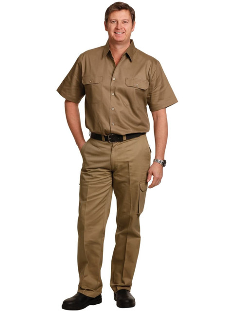 A man wearing khaki work pants with pockets on the legs and a matching short-sleeved shirt, standing with a belt. A man wearing khaki work pants with pockets on the legs and a matching short-sleeved shirt, standing with a belt.