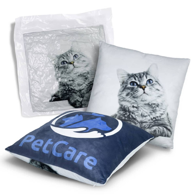 A plush cushion featuring a grey cat design and a blue PetCare logo, packaged in a clear plastic cover. A plush cushion featuring a grey cat design and a blue PetCare logo, packaged in a clear plastic cover.