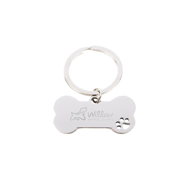A silver dog bone keytag featuring a paw print design and an engraved logo.
