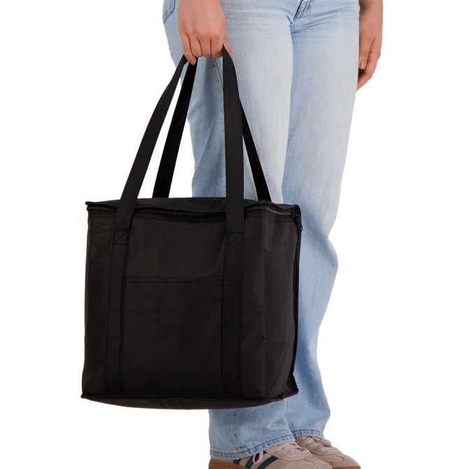 A black cooler bag with dual handles, held by a person wearing light blue jeans. It features a simple design and has a logo.