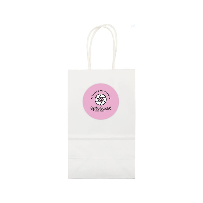 A small white paper bag with handles and a circular logo in pink on the front.
