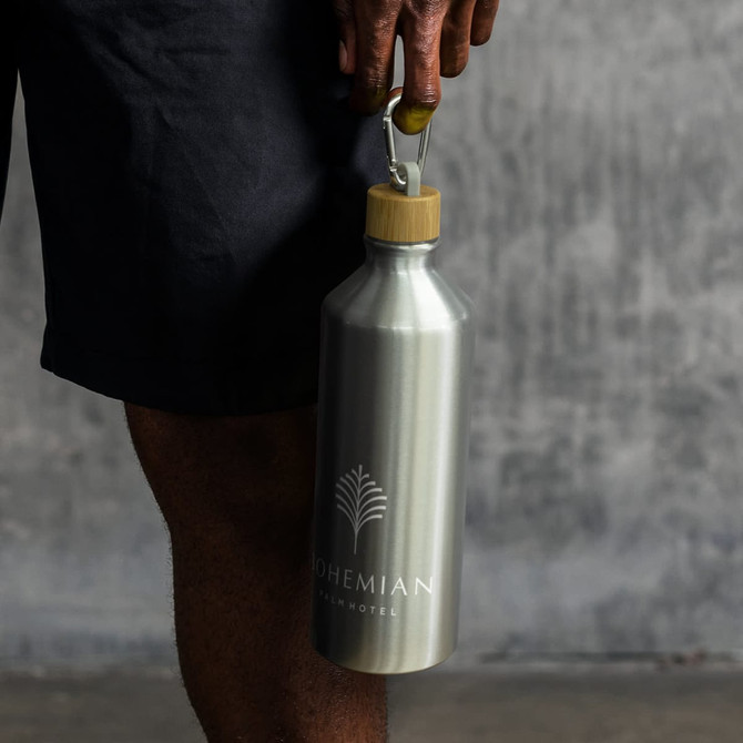 A drink bottle with a silver aluminium body and a bamboo lid, featuring a logo.