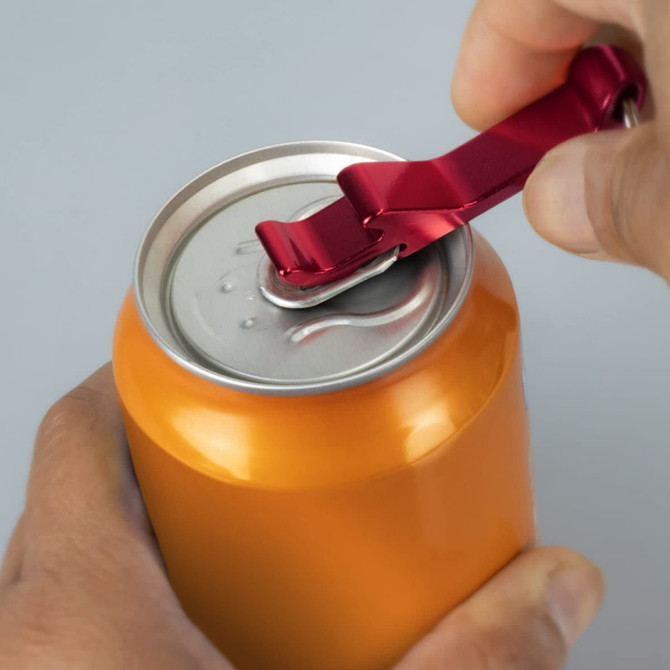 A drink bottle opener in red is being used to open a can with an orange body. The product includes a key ring.