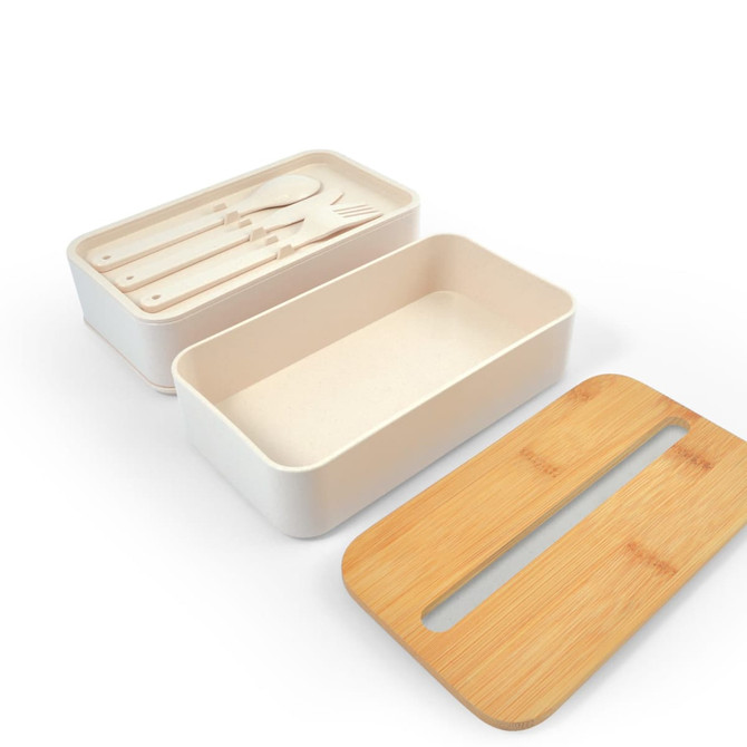 A cream-colored eco lunch box with a bamboo lid and an insert containing utensils.