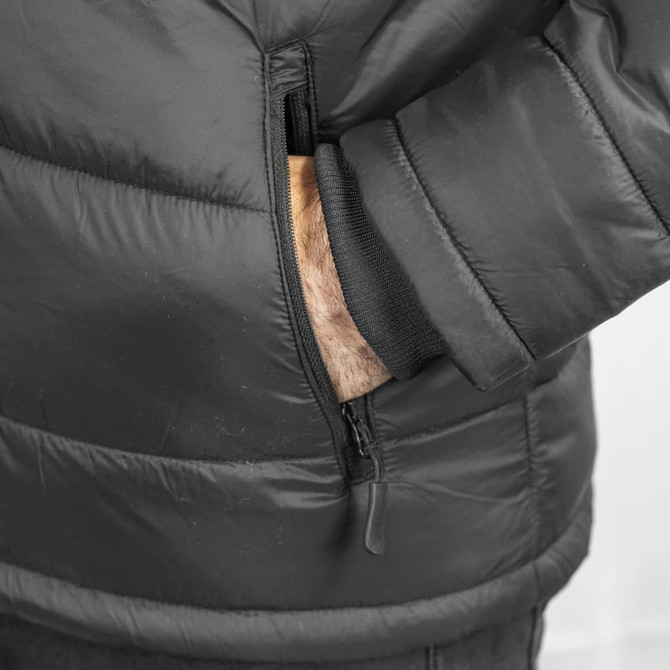 A black puffer jacket featuring a zippered pocket and cuffed sleeves. The hand is visible in the pocket.