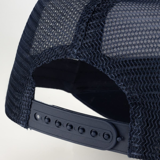 A trucker cap in navy blue featuring a mesh back and an adjustable strap for fit. It includes a logo on the front.