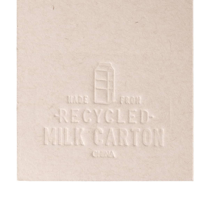 A cream-colored bookmark designed to resemble a milk carton, featuring embossed details and a logo.