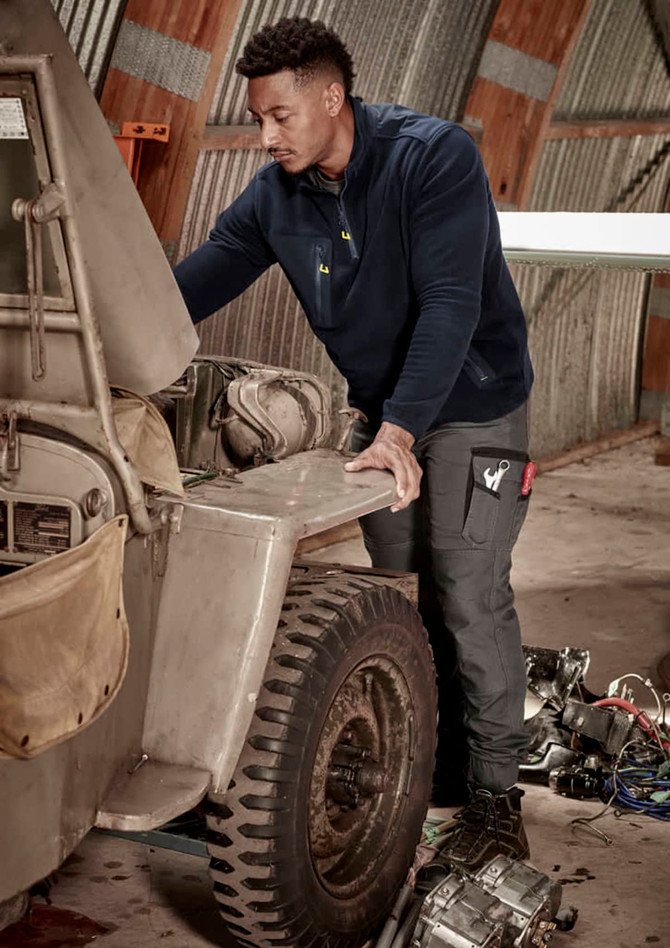 Men's Streetworx Heritage Pant in dark grey, worn by a man working on a vehicle in a garage setting.