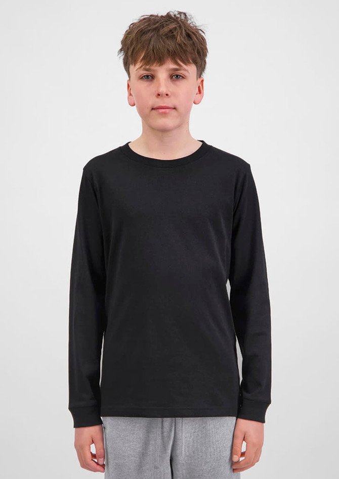 A youth long sleeve tee in black, featuring a simple design and long sleeves. The model stands against a plain background.