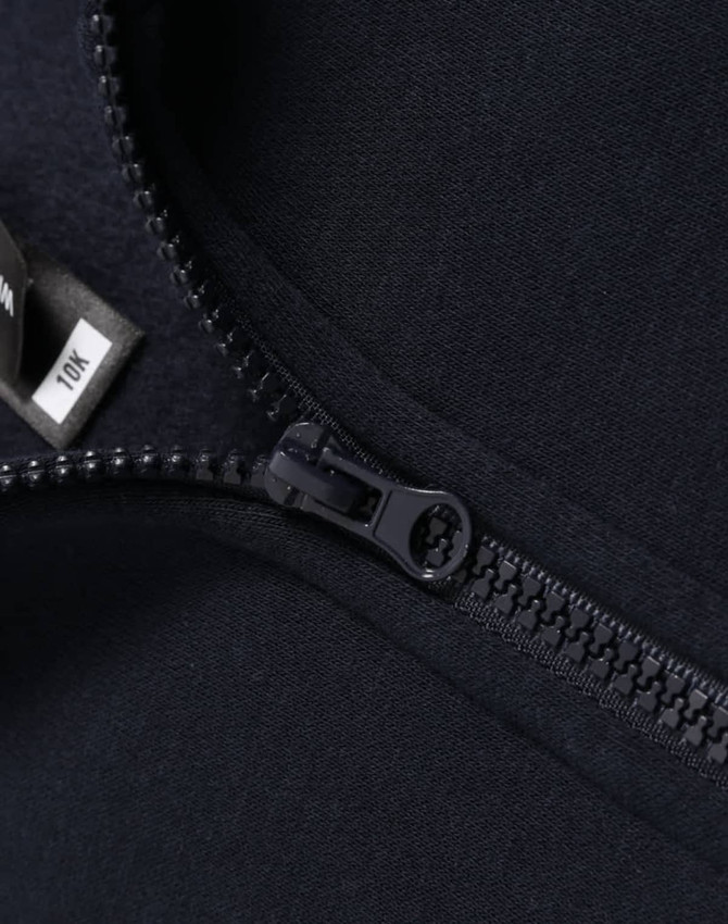 A close-up of a navy 1/2 zip collar fleece sweatshirt featuring a zipper and a tag.
